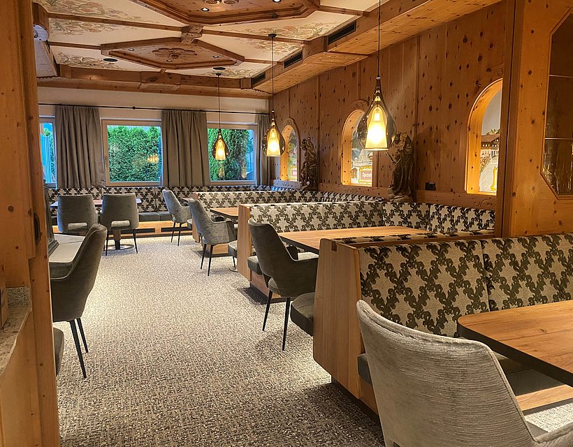 Gemütliches Hotelrestaurant mit Holzwänden, Polsterbänken, Pendelleuchten und Alpenflair