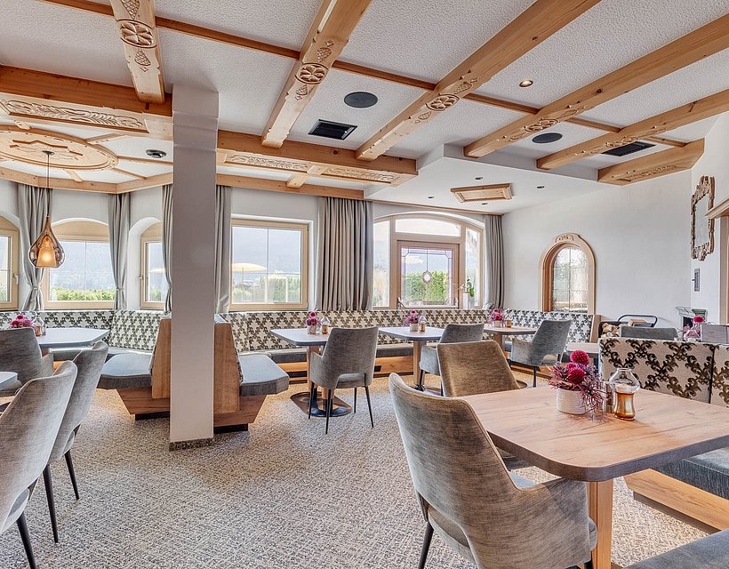 Heller Speisesaal im Hotelrestaurant mit gemütlichen Sitzgruppen und alpiner Holzdecke