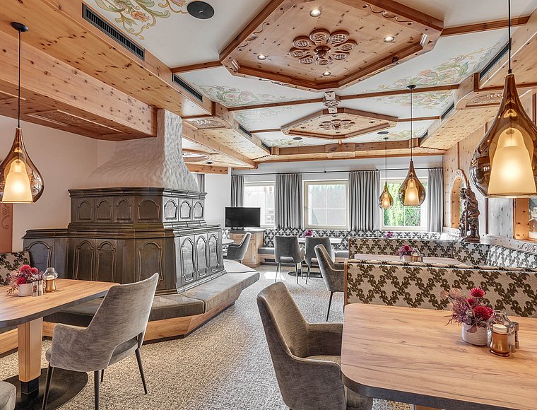 Traditional hotel restaurant with a rustic tiled stove and ornate wooden ceiling