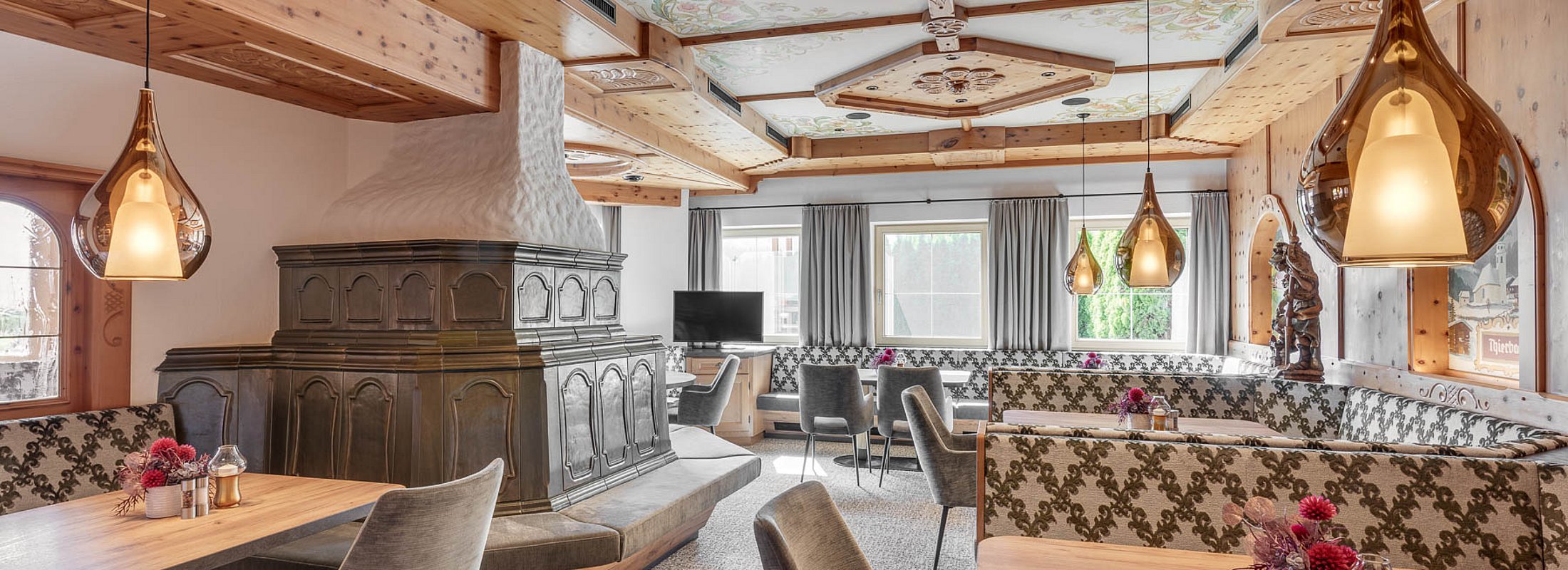 Traditionelles Hotelrestaurant mit rustikalem Kachelofen und kunstvoller Holzdecke